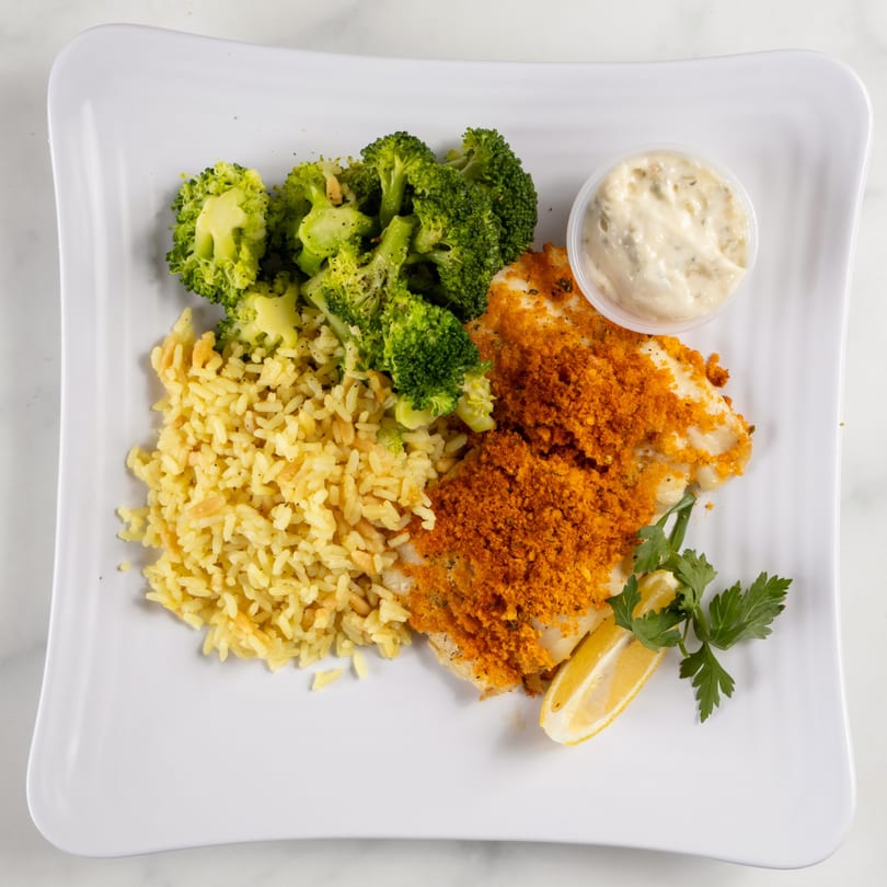 Breaded fish with rice, broccoli, lemon, parsley, and tartar sauce on a white plate.