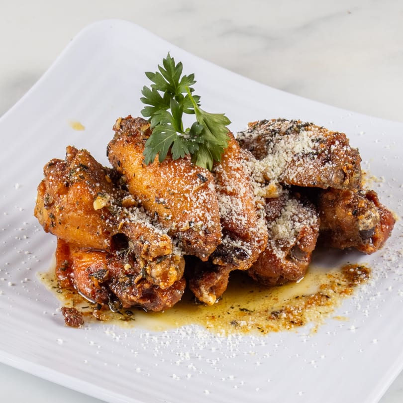 North End Market & Deli's chicken wings, garnished with parsley and parmesan cheese, on a white plate.
